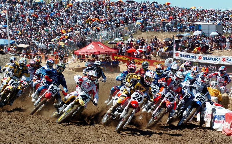 Hangtown 05 Ernesto Fonseca (24) leads the pack into the first turn in front of a big crowd at the 2005 AMA Motocross Championsip season opener, the Hangtown Classic. Others in the photo include from left John Dowd (16), Rodrig Thain (50), Ricky Carmichael (4), Kevin Windham (14) and Chad Reed (22). (Larry Lawrence photo)