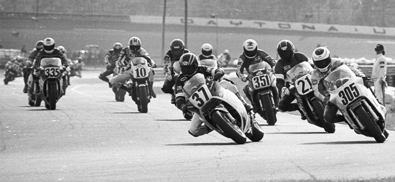 John Ashmead leads a gaggle of riders entering the International Horseshoe during the 1987 Daytona 200 by Arai. Others braking for the horseshoe include David Strobel (305), Keith Pinkstaff (21), Rodney Farris (351), Doug Chandler (10), Doug Chancey (335) and others. (Larry Lawrence photo)