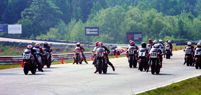 Suz v Yam WERA Rd. Atl. May '86 This WERA A Production race at Road Atlanta in May of 1986 showed the early club-racing battles between Yamaha FZ750 and Suzuki GSXR750 riders. On Yamaha’s you have “Rocket Ron” Ewerth (21), Jeff James, Wink Price (63), Doug Roy (209), Bob Englert (298) and novice Dennis Martin (445) on Yamahas, while Greg Tysor (67), David Harman (528), Mark McQuade (52) and Greg Goulding (directly behind #21 Ewerth) were on the new Suzuki. Buck Clemson was the odd man out riding a two-stroke Yamaha RZ500. (Larry Lawrence photo)