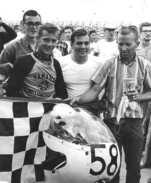 Meadowdale - Nicholas 1963 Winners' circle photo after first win by a Yamaha in AMA national competition – 1963’s Meadowdale 100 mile AMA 250cc event. Left to right: Pat Gardiner, fellow student and fraternity member of Nicholas at the University of the South, Jody Nicholas, John DiSimone, mechanic and Tom Clark, AMA official. “I felt sort of guilty,” Nicolas said. “That little two-stroke was so fast compared to the Harley Sprints. Nixon and Roeder were on Sprints and I just walked away from them.” (Nicholas Collection)