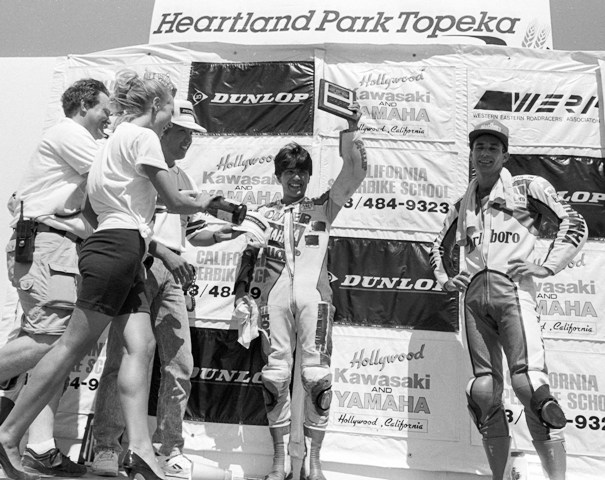 Arata - Topeka FUSA 1990 Tatsuro Arata (holding up trophy) celebrates his victory in the WERA Pro Formula USA race at Heartland Park Topeka in July of 1990. Rich Oliver stands next to Arata. He rode a Yamaha TZ250 to third. Second-place finisher Mike Smith is obscured by the others on the podium. (Larry Lawrence photo)