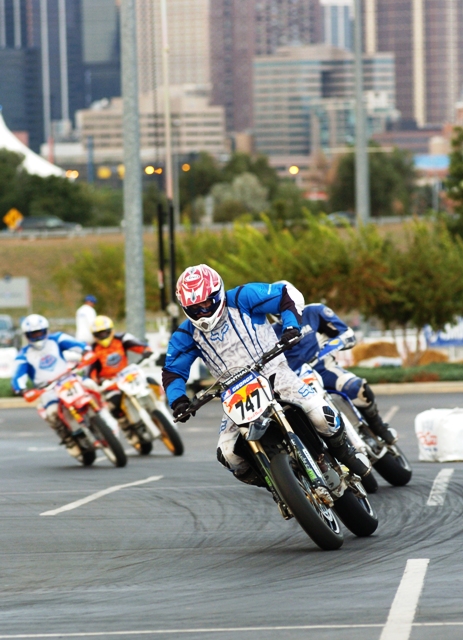 George - Denver SuMo '06 Jesse George, of Independence, Mo., leads the pack in the Denver AMA Supermoto in the parking lot of INVESCO Field at Mile High in August of 2006. You can see buildings in downtown Denver in the background. It was one of the really cool locations that typified AMA Supermoto racing during the mid-2000s. George was racing for Jardine`s/Fat Boy Racing/Michelin Suzuki and finished 15th and 16th in the two Denver rounds. (Larry Lawrence photo)
