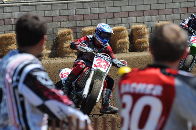 A couple of racers stand at the fence and check out AMA Pro Singles rider Levi Mayer taking a corner during practice for the Springfield TT last month. You often see top riders getting just a little bit of an edge on the competition by taking in some of the practice sessions trackside and studying the lines other riders are taking. (Larry Lawrence photo)