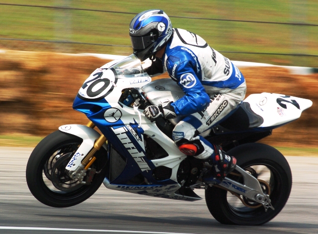 Here’s photo evidence of Aaron’s sometimes non-conventional Superbike riding style. Notice the seriously compressed rear tire on the Jordan Motorsports Suzuki. That’s because Aaron is landing the bike after jumping over a curb. Oh and he jumped over the curb all the while doing a wheelie. Aaron’s one of the riders really missed in the series. (Larry Lawrence photo)