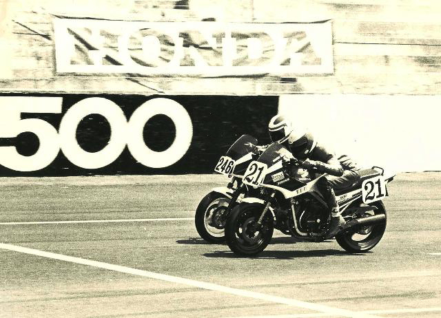 Ewerth - Rockingham Ron Ewert (21) and Jeffrey Dean (246) engage in a wheel-to-wheel battle just as they pass under a combination banner/wall that read “Honda 500” – appropriate since both riders were on Honda 500 Interceptors. (Larry Lawrence photo)