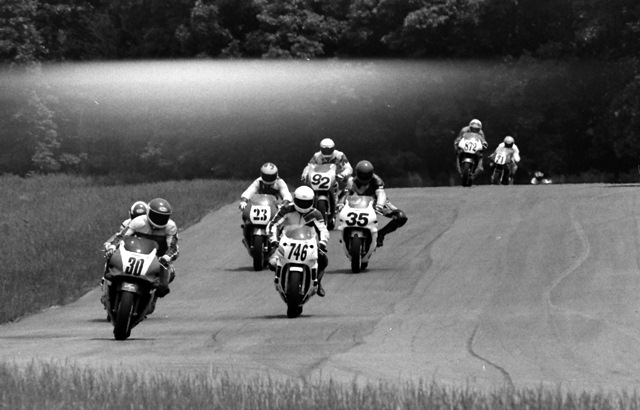 Putnam Fog This could be fogging of the film instead of a real fog bank, but I think the result was kind of cool anyway. It’s from a WERA North Central Sprint race at Putnam Park Road Course in June of 1992. I’m guessing this was a C Superstock race. I’m not certain who the leader No. 30 is, maybe Ramon Vasquez. I do recognize Bill Sweeney (No. 746), Stacy VanHoy (No. 23), Reuben Frankenfield (No. 35), Matt Macheca (No. 92), Kris Badger (No. 872) and Darrell Wenke (No. 21). (Larry Lawrence photo)