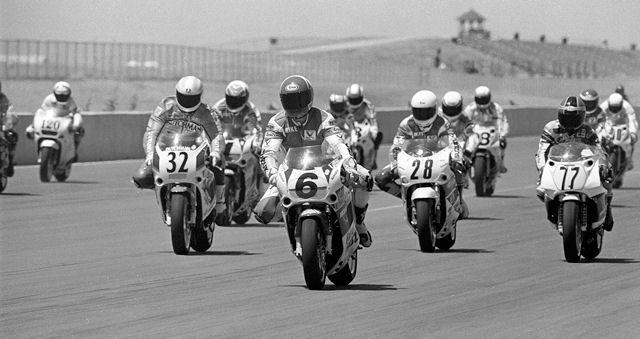 Smith - Topeka FUSA '90 Mike Smith (No. 6), on his Valvoline Suzuki GSXR1100, leads the pack into the first turn in the WERA Pro Formula USA Series race at Heartland Park Topeka (Kans.) in July of 1990. Tatsuro Arata (No. 77) on a Moto-Liberty sponsored Yamaha (No. 77) won the race with a late-race pass on Smith. Also visible in the photo are Dale Quarterley (No. 32), Britt Turkington (No. 28), Kurt Hall (No. 1) and Chuck Graves (No. 120). (Larry Lawrence photo)