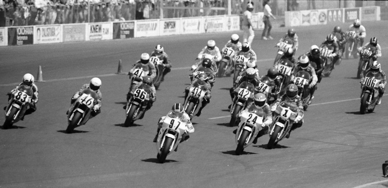 Oliver - Sears Point '86 Rich Oliver leads into the first turn at the Sears Point AMA 250 Grand Prix in May of 1986. Following Oliver are James Stephens (No. 24) and eventual race winner Donny Greene (No. 1). It should be noted that those three were all Northern California riders who had tons of experience at the track. This was a race chalk full of talented racers. Also visible in the shot are Ed Key (No. 83), Doug Brauneck (No. 46), Randy Renfrow (No. 96), unknown rider (No. 414), John Long (No. 42), Keith Kiyota (No. 34), Jeff Heino (No. 64), Gary Tatsumi (No. 106), David Curtis (No. 47), Gordon Hedemark (No. 16), Allan Scott (No. 29), Robert DeWitt (No. 87), Andrew Price (No. 31) and several more near the back. (Larry Lawrence photo)