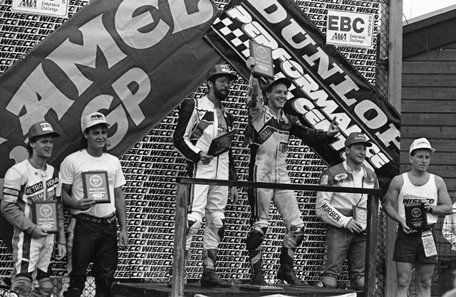 Mid-O GTU podium 1990 GTU winners celebrate on the podium after the EBC Brakes Challenge at Mid-Ohio Sports Car Course in August of 1990. Standing atop the podium are GTU winners Thumper Brothers, Bill Cardell and John Condron (holding up plaque). Northstar GTU (standing left) took second with Scott Ruehle and Mike and third was Norben Racing’s Jim Kosar and Ralph Johnson (right). (Larry Lawrence photo)