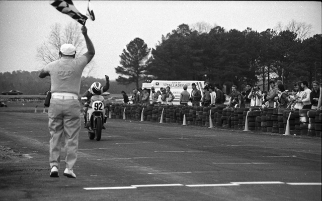 Nardiello, Steve - Talladega 2-86 Steve Nardiello celebrates as he takes victory and receives the checkered flag from legendary race starter “Airborne Al” Wilcox in a WERA sprint race at Talladega Gran Prix Raceway in February of 1986. (Larry Lawrence photo)