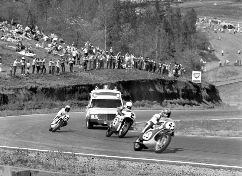 Rd Atl '71 ama national Bob Bulmer (No. 43), Jim Rice (No. 2) and Ron Pierce (No. 37) race through turn five at Road Atlanta while they share the track with the track ambulance during the AMA National Road Race in 1971. Funny thing is 20 years later I shot the very same angle with what I think is the same ambulance on the track. Pierce, along with teammate Jody Nicholas, were both disqualified in one of the more bizarre DQs in AMA racing history. For some reason the factory Suzuki team decided to set up their pits back in the back section of the track off turn seven. It sounds crazy, but my guess is Suzuki posted a crew member out there with a gas can to fill up Pierce and Nicholas’ motorcycles during the race to save time rather than pull into the regular pit area. This photo is part of the excellent Bud Turner Collection. (Bud Turner photo)