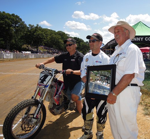 Carr, Chris - Peoria 2011 presentation Chris Carr receives a special Lifetime Achievement award from Bert Sanders of the Peoria Motorcycle Club during the 2011 edition of the prestigious Peoria TT. His longtime mechanic Kenny Tolbert is holding Carr’s bike. Over the years Carr became known as the Prince of Peoria. His record at Peoria is stunning. He won 13 nationals at the track, by far the most of any rider. (Larry Lawrence photo)