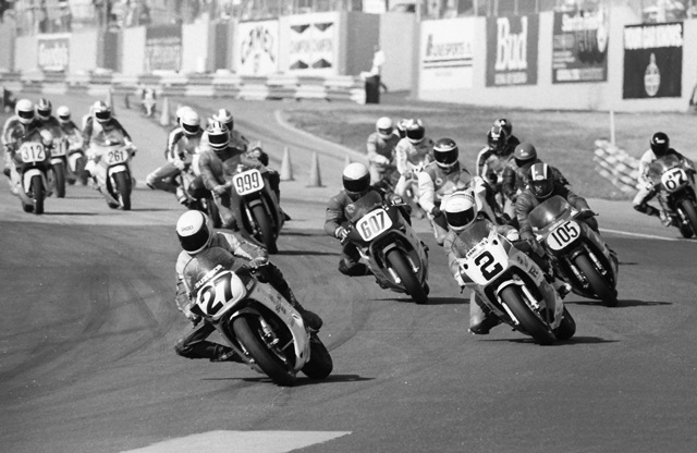 Texan Wesley Winchester (No. 27) leads the field going into turn one on his Suzuki GSXR750 at the start of the WERA B Superbike final during the 1987 Grand National Final at Road Atlanta. Also visible in this photo are Kurt Hall (No. 2), Jeff Harder (No. 105), Graham James and Eric Moe (directly behind Harder), Tony Rauseo (No. 607), Greg Tysor (No. 67), Cam Roos (No. 312), Fritz Kling (behind Roos) and Robby Braunscheidel (No. 261). Kevin Rentzell stalled his bike at the start, but charged through the field to win. (Larry Lawrence photo)