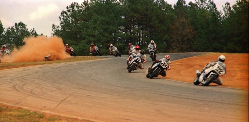 GNF dustup 1987 An unidentified rider kicks up a major cloud of red Georgia clay as he crashes out of the first lap of the 1987 WERA A Production Final at the Grand National Final, which is led by and eventually won by Scott Russell. (Greg Sickmeier photo)