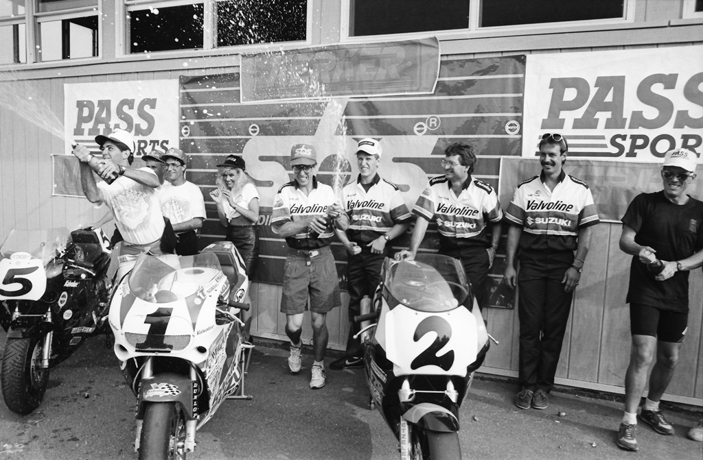 Michael Martin (left), Kurt Hall (center) and Andy Fenwick (right) spray champagne during podium celebrations after the WERA National Endurance at Grattan Raceway in July of 1990. One member of the winning Valvoline-sponsored Team Suzuki Endurance team was missing from the podium. That was Britt Turkington, who was on his way to the hospital to be checked out after crashing on the final lap. Team Suzuki still won in spite of the crash. (Larry Lawrence photo)