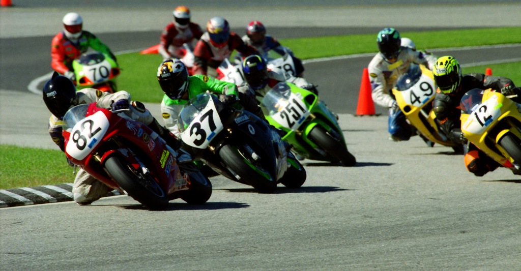 Des Conboy flicks his Yamaha R1 through the first set of turns in front of the field at New Hampshire International Speedway in Loudon, N.H., at the start of the Unlimited Superbike race during the AMA Road Race Grand Championships in September of 1999. Conboy dominated the race, winning by 18 seconds. Following Conboy at the start of the race is Michael Martire (No. 37), John Scheehser (No. 12), Bob Blanchette (No. 251) and Rick Maron (No. 49). Also visible in the group is Tim Bemisderfer (No. 511), Brandon Bashore (No. 78) and Robert Kessell (No. 70). (Henny Ray Abrams photo)