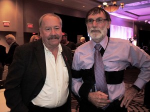 Jim Allen (on right with arm in a sling after a recent shoulder repair surgery) was inducted into the Canadian Motorcycle Hall of Fame. Standing with Allen is fellow Canadian Hall of Famer George Morin. (Photo & Story by Colin Fraser)