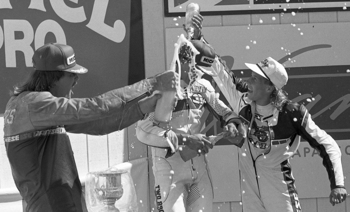 Kevin Erion celebrates his race and championship victory at the 1988 AMA Pro Twins Modified Production season finale at Sears Point with second-place Aaron Rueger pouring champagne on Erion’s head, with third-place Ward Rodgers popping the cork as well. Erion won the title in his rookie season. (Henny Ray Abrams photo)